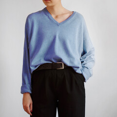 Young woman wearing light blue sweater and black trousers with belt isolated on white background.