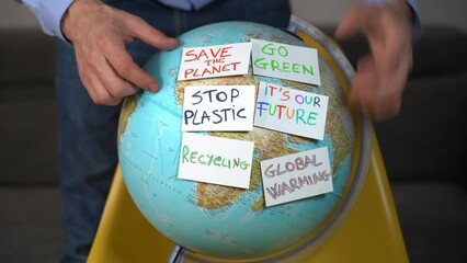 Man hands  touch  Earth globe with stickers with the message Save the Planet, Help and No Plastic, Recycling, SOS. Concept save our planet and climate change due  global warming 
