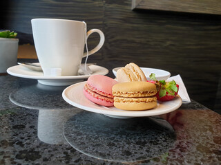 Plate of colorful macarons and a tea cup as an afternoon snack