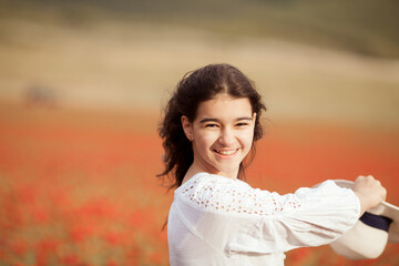 Beautiful girl in a white dress on a poppy field