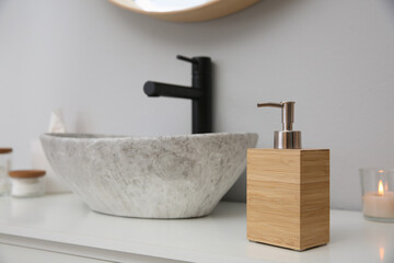 Wooden dispenser of liquid soap near sink in bathroom. Space for text