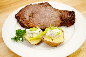 A Broiled Prime Rib Steak Served with Baked Potato and Scallions