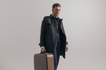 attractive businessman in suit with long coat holding briefcase