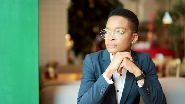 African American female thinking while sitting in a cafe, a serious thoughtful pensive business woman looking out the window. businesswoman employee entrepreneur sitting. startup and case resolution