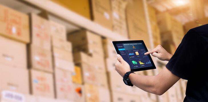 Smart Inventory management system concept.Manager using digital tablet,showing warehouse software management dashboard on blurred warehouse as background