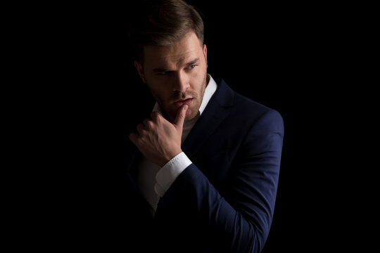 seductive young man in suit holding finger to lips and being sexy