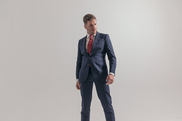 confident elegant man in suit looking to side and standing