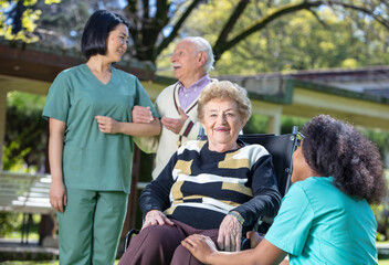 Caucasian seniors smiling with nurses outdoor. Retired elderly people living their life at its best.