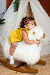 little african, black girl is rocking on a rocking-horse. baby with dark skin color smiling