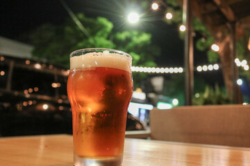 glass craft beer in the bar with lights behind the night in the pub