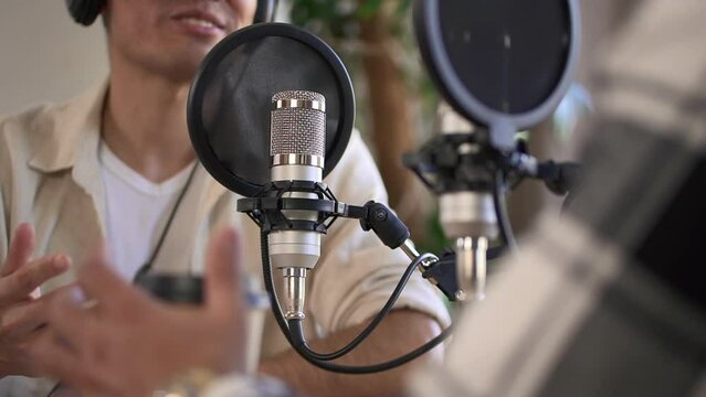 Man record audio mic content or conduct a radio program with coworker in recording studio Spbd. Closeup on microphone with pop filter. Male gesture. Concept podcast, interview