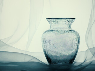 Crackle glass vase with net curtain, still life.