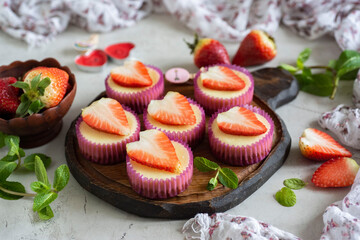 Romantic breakfast: Strawberry mini cheesecakes for breakfast for a loved one on a beautiful dish with strawberries on a gray table. Close-up