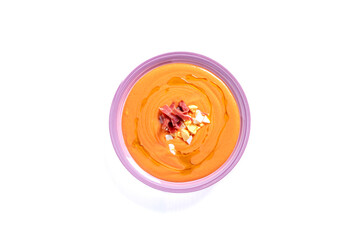 Round plate with salmorejo on a white background, accompanied with egg and ham.