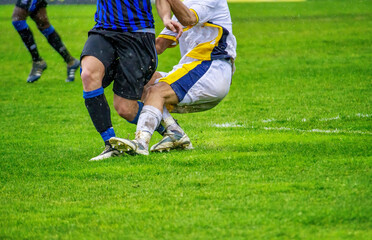 Soccer players tackling in the football pitch.