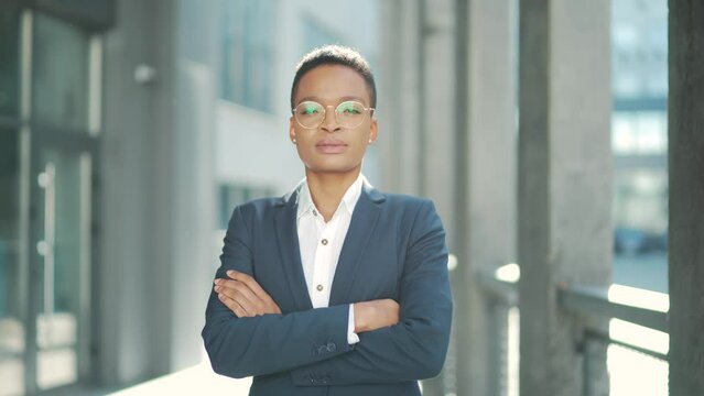 portrait of confident serious african american business woman standing with arms crossed looking at camera. outdoors. Independent female teacher or associate professor with glasses on the outside