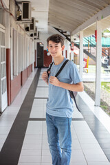 High school male student walking down the hallway looking to the camera.