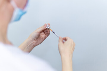 Nurse filling syringe with medication of a vial, health care and vaccination concept