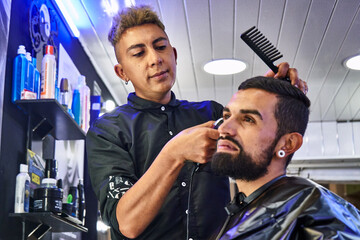 un hombre joven se esta haciendo un corte de pelo en una barbería de su cuidad