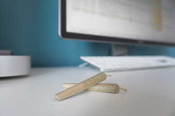 Winnipeg, Manitoba, Canada - February 12, 2022: Close-up of Pre Rolled Joints with an Unfocused Computer in the Background.