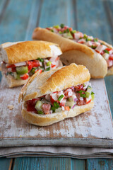 Delicious sandwiches with baguette and crab meat on a bright blue wooden background