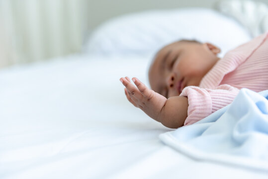 Blurred soft images of an African baby newborn sleeping and lying on a white bed, to African child concept.