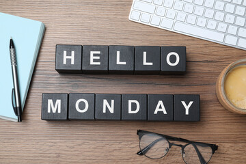 Black cubes with message Hello Monday, office stationery and cup of coffee on wooden desk, flat lay