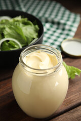Obraz na płótnie Canvas Jar of delicious mayonnaise and fresh salad on wooden table