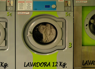Green interior of a public self service laundry. Washing machines with coin-operated laundromat....