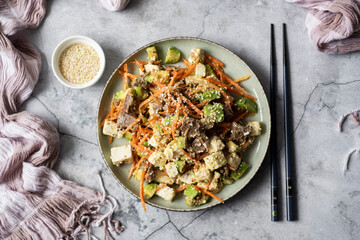 Korean dish: Salad with Korean carrots, olives, spices and feta, seasoned with olive oil on a beautiful plate on a gray background. Top view