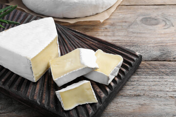 Tasty cut brie cheese on wooden table