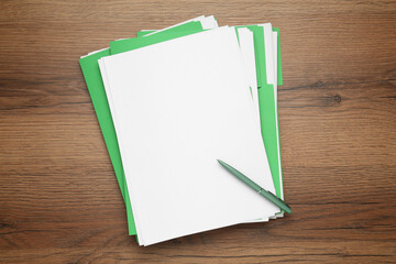 Light green files with blank sheets of paper and pen on wooden table, top view. Space for design