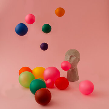 A sculpture of an Asian blowing colorful balloons flying in all directions on a pink background
