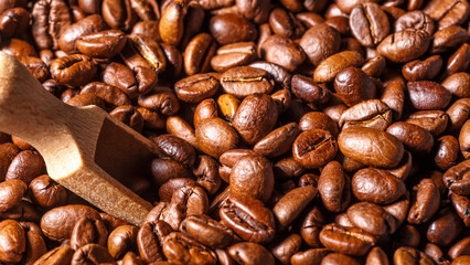 Freshly roasted coffee beans background.Dark roasted coffee beans with scoop on wooden background.