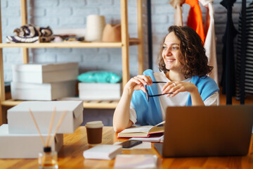 Young woman takes notes of orders from with laptop. Dropshipping business owner working in her...