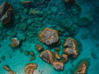 directly above woman in red swimsuit at the rock surrounded by the sea