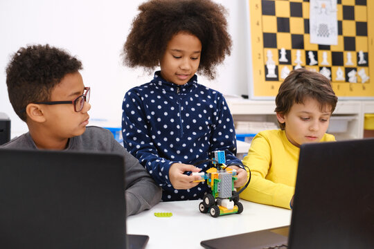 Kids learning coding, science and technology at school class. African American and Caucasian children studding with laptop computers on STEM lesson. Diversity in modern innovative education