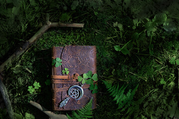 magic witch book and wiccan amulet with pentagram on natural dark forest background. Esoteric...