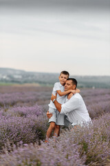 A young man and his son are walking through a beautiful field of lavender and enjoying the fragrance of flowers. Rest and beautiful nature. Lavender blooming and flower picking.