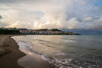 Beach with city view at sunset, cloudy sky