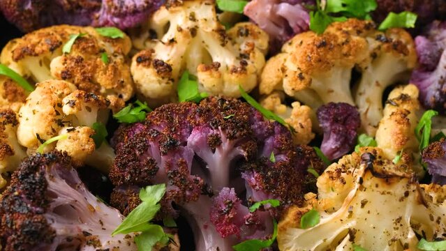 Roasted purple, white cauliflower with herbs. Rotating video.