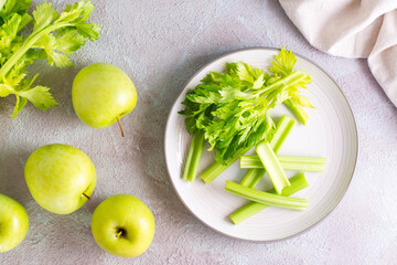 Sliced fresh celery stalk with leaves on a plate and green apples on the table ready to be cooked. Vegetarian food. Top view