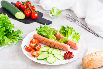 Ready-to-eat fried sausages and fresh vegetables on a plate on the table. Hearty homemade snack