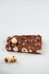 Delicious milk chocolate bars with nuts close up. Stack of chocolate slices Hazelnut pieces tower. Sweet food photo concept