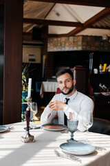 A young bearded male businessman is sitting at a table in a fine restaurant and waiting for his order. Customer service in the catering.