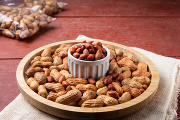 Peanuts falling into a snack bar, on a red wooden table.