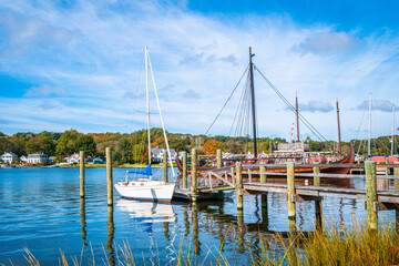 Commercial dock with moored white boat and sailing ship in Mystic, Connecticut