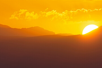 The sun rising early in the morning above the hills of Greece.