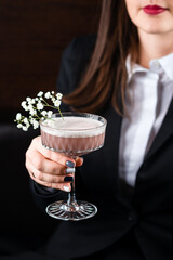 light pink elegant cocktail with egg white froth in a woman's hand