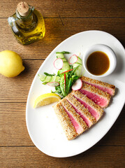 Traditional Japanese salad with medium-fried tuna Ahi slices on the grill and sesame seeds with a salad of fresh vegetables on a plate. Top view. Space for copying. Serving tuna in a restaurant. Japan